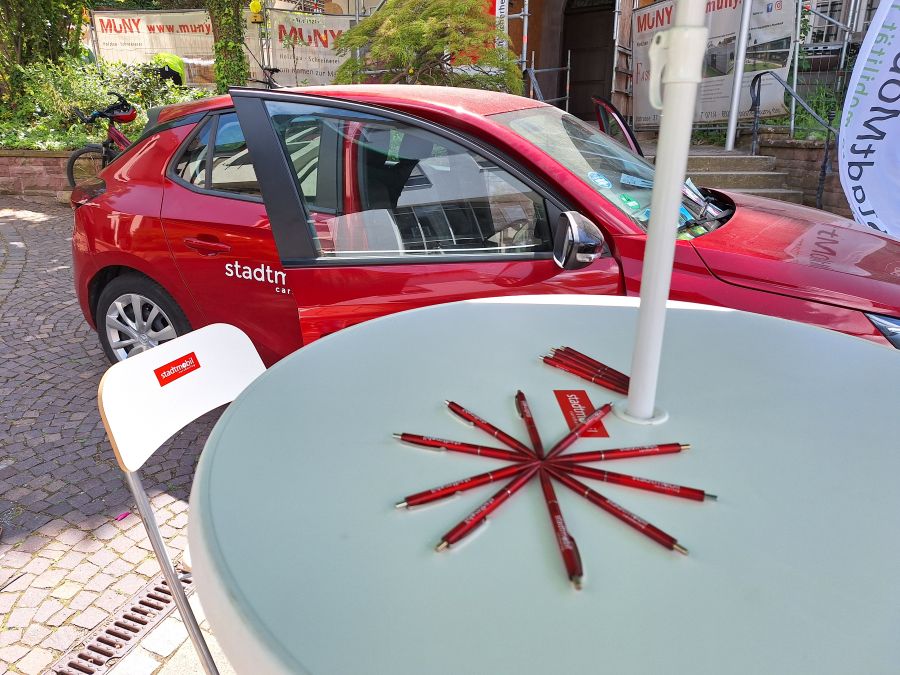 Infostand mit offenem Auto und Bistrotisch